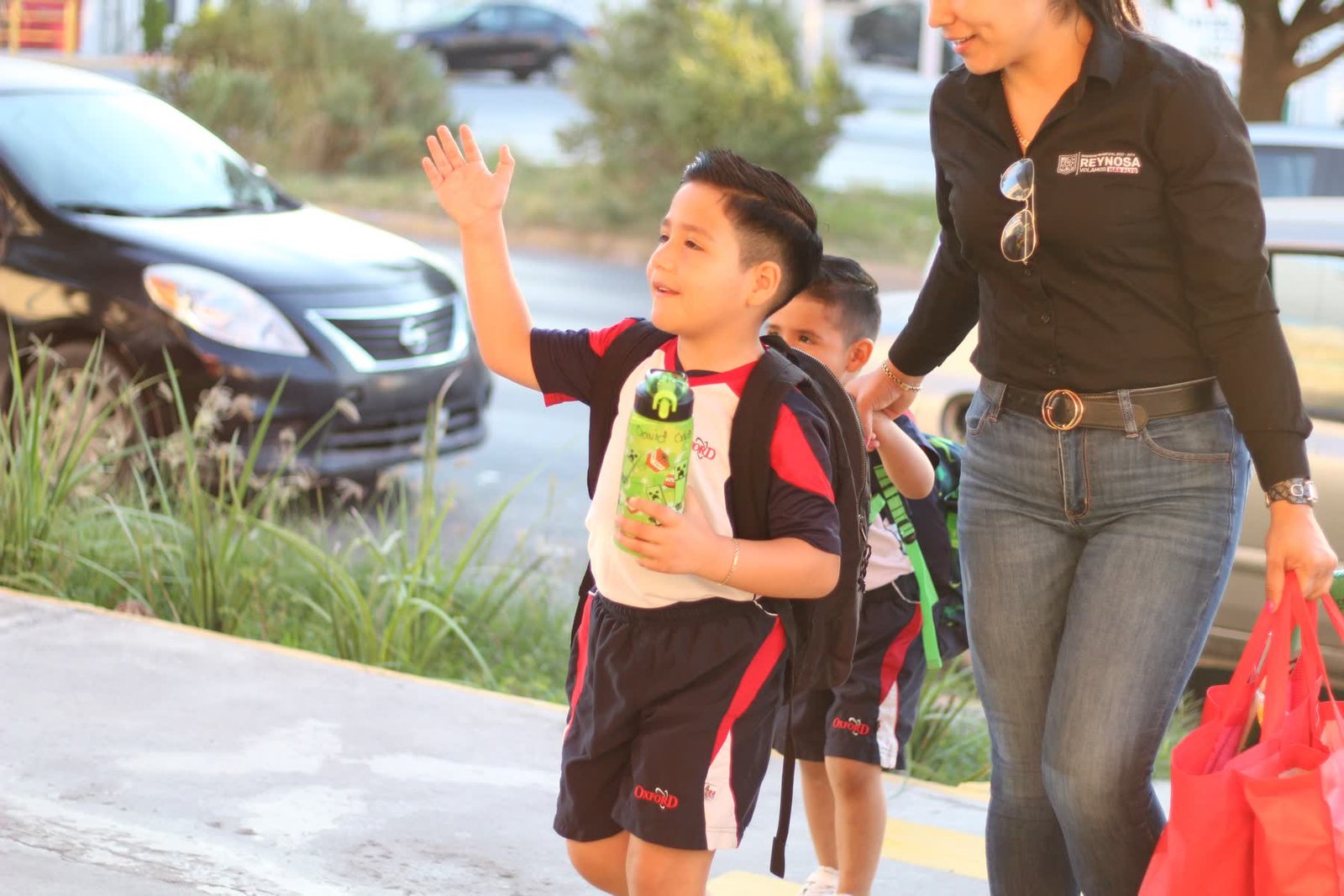 A pupil waving as he is collected at the campus gate