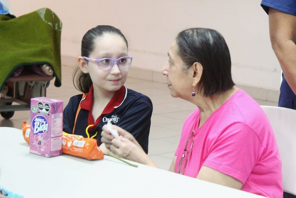 A Vista Hermosa student spending time with an older neighbour on a community visit