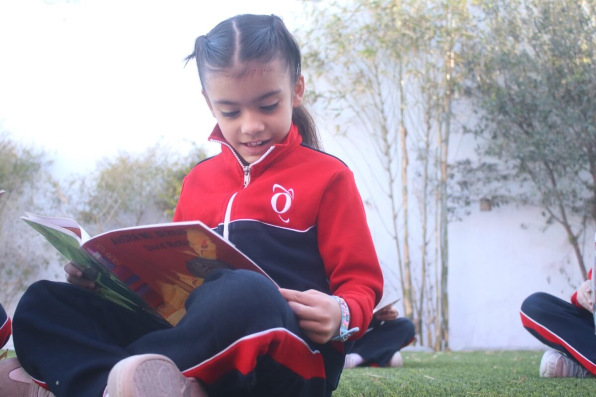 Las Fuentes pupil reading a picture book on the grass