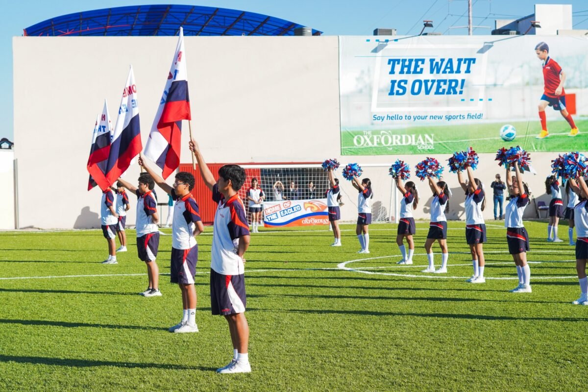 Students with flags and pompoms at the opening of the new sports field