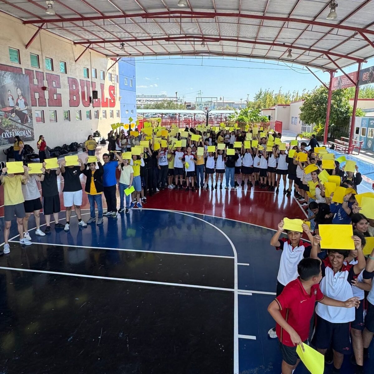 Students and staff gathered on the covered court, each holding up a yellow sheet of paper.