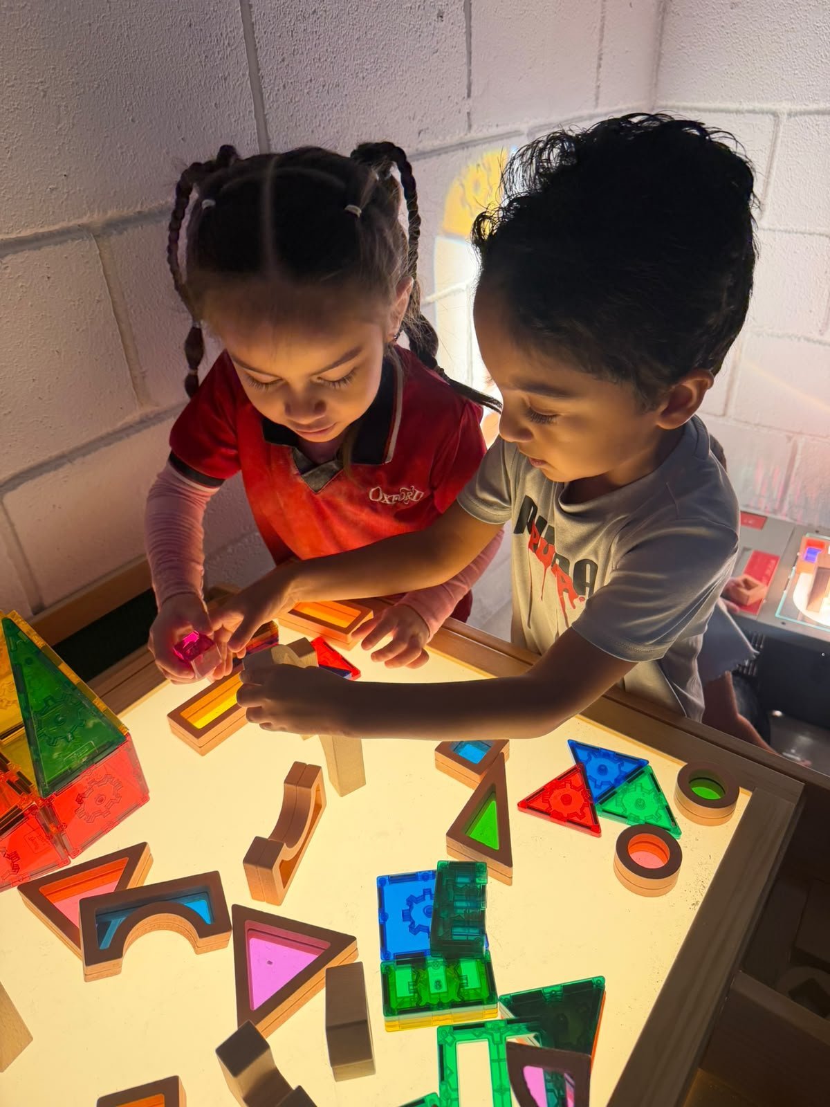 Two children building with coloured blocks at a light table